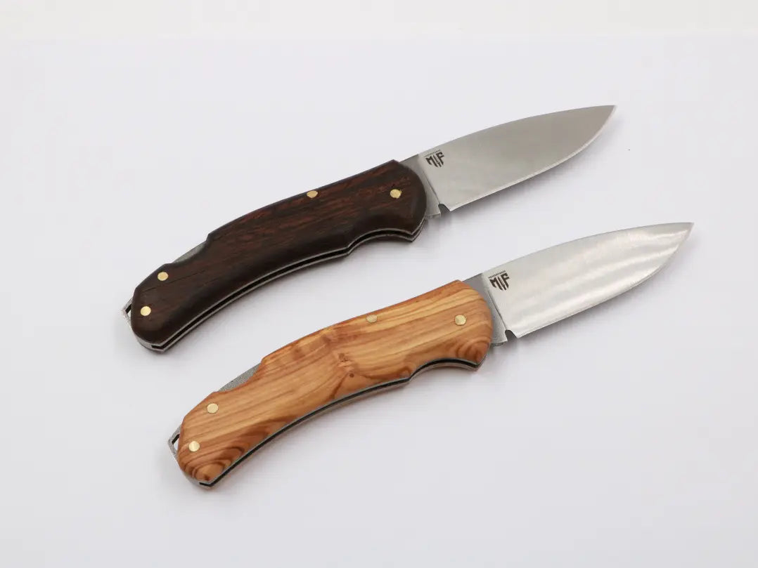 „Zwei MF Little Uiguren Slipjoint-Messer mit Holzgriff – einmal in dunklem, einmal in hellem Holz. Elegante Handarbeit mit klassischer Klinge.